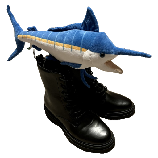 A plush marlin sitting on top of a pair of black combat boots